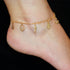 A foot adorned with the "Women Mega Lucky Charm Anklet Bracelet," featuring 14k gold-filled amulets such as a pear-shaped crystal, pentagram, seahorse, Hamsa hand, and anchor for good luck and evil eye protection, is set against a black background.